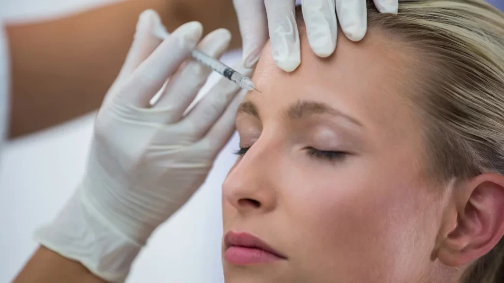 Une femme reçoit une injection de neuromodulateur dans le front.
