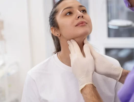 A woman receives a neck examination from a doctor, focusing on health and potential solutions for a double chin.