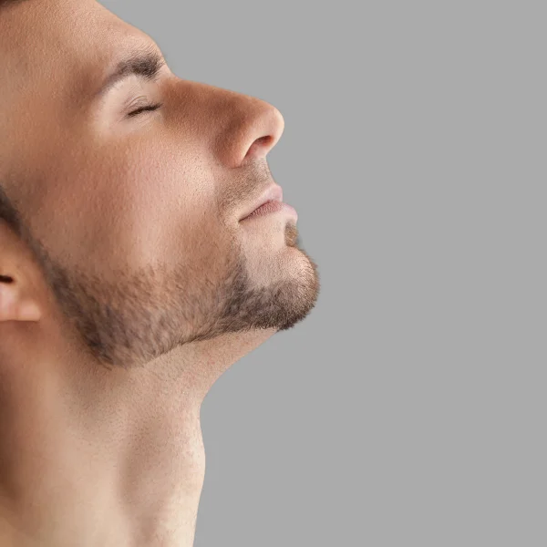  A man with his eyes closed and head tilted upward, demonstrating relaxation while addressing double chin concerns.
