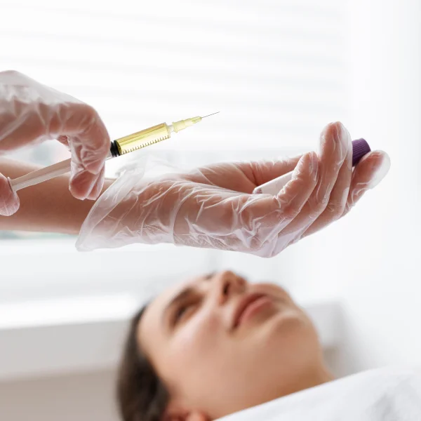 A woman receiving an injection in her arm, part of a facial rejuvenation treatment.